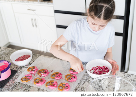 With focused attention, this budding culinary artist dips pretzels into a pot of melted chocolate, creating sweet delights in the warmth of a well-lit home kitchen. With focused attention, this budding culinary artist dips pretzels into a pot of melted chocolate, creating sweet delights in the warmth of a well-lit home kitchen. 123907672