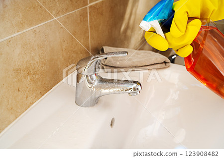 Cleaning bathroom water tap, yellow gloves and spray detergent 123908482