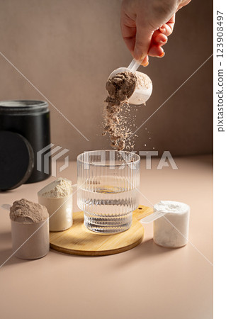Chocolate protein powder pouring in a glass. Food supplement, fitness sport, health and nutrition. Chocolate protein powder pouring in a glass. Food supplement, fitness sport, health and nutrition. 123908497
