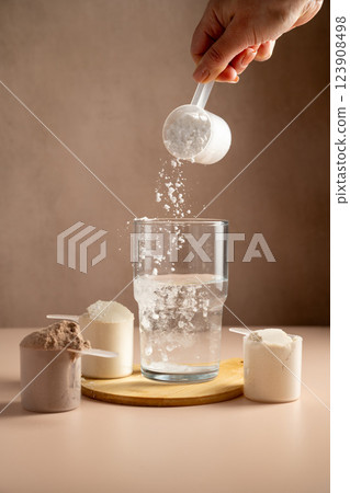 Collagen, creatin powder pouring in a glass. Food supplement, fitness sport, health and nutrition. Collagen, creatin powder pouring in a glass. Food supplement, fitness sport, health and nutrition. 123908498