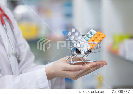 woman pharmacists holding shopping trolley with set medicine in drug store. pharmacy and health care online concept. 123908777