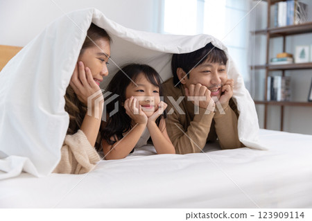 Happy father mother daughter lie down and play on bed. Mom dad and little girl smiling cheerful bedroom. relaxing in holiday. Happy father mother daughter lie down and play on bed. Mom dad and little girl smiling cheerful bedroom. relaxing in holiday. 123909114