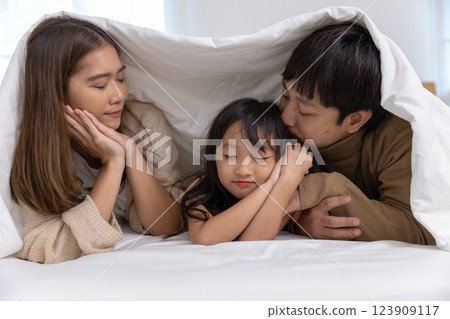 Happy father mother daughter lie down and play on bed. Mom dad and little girl smiling cheerful bedroom. relaxing in holiday. Happy father mother daughter lie down and play on bed. Mom dad and little girl smiling cheerful bedroom. relaxing in holiday. 123909117