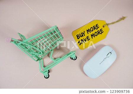 Buy More Save More text on price tag with optical mouse and trolley shopping cart on pink background Buy More Save More text on price tag with optical mouse and trolley shopping cart on pink background 123909736