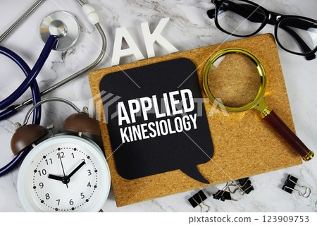 AK Applied Kinesiology acronym with alarm clock and magnifying glass, medical and healthcare concept background 123909753