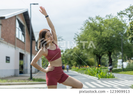 Young beautiful woman sportswear workout clothes using smartphone and listening to music with headphones standing relax in park during exercise the morning. fitness healthy concept. Young beautiful woman sportswear workout clothes using smartphone and listening to music with headphones standing relax in park during exercise the morning. fitness healthy concept. 123909913