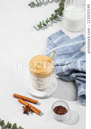 Dalgona coffee in a glass on a light background with spices and napkin. 123910146