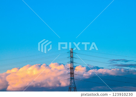Tokyo cityscape in Japan. Summer-like clouds turn orange in the setting sun... Power pylons and transmission lines... What is the future of energy? 123910230