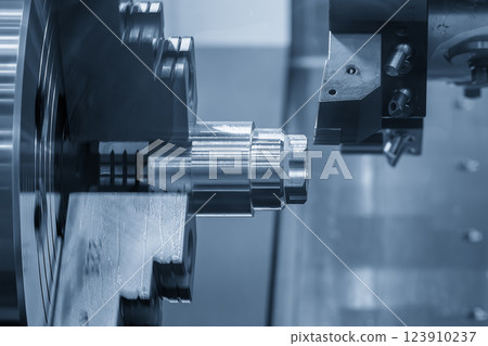 The CNC lathe machine forming cutting the metal shaft parts in the light blue scene. The CNC lathe machine forming cutting the metal shaft parts in the light blue scene. 123910237