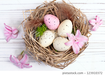 Easter nest with speckled eggs, moss and pink flowers. Easter nest with speckled eggs, moss and pink flowers. 123910372