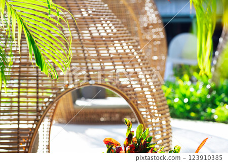 Egg-shaped cozy wicker lounge bed in a tropical garden Egg-shaped cozy wicker lounge bed in a tropical garden 123910385