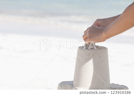 Summer vacations, hand of a kid is constructing a sand castle. 123910386