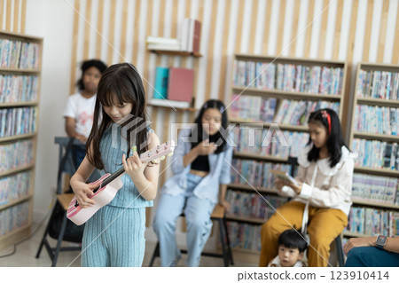 School children education practicing playing the ukulele in classroom. kid schoolgirl happy learning. Writing as instructed by teacher. concept of back to school. 123910414