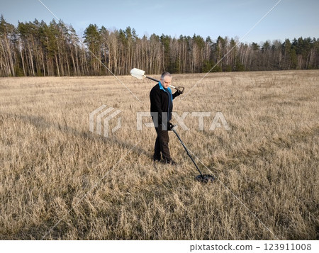 man with a metal detector. Man with electronic metal detector device in his hand. 123911008