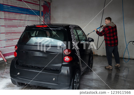 Woman washing her car in a self-service car wash station.Car wash self-service. Woman washing her car in a self-service car wash station.Car wash self-service. 123911566