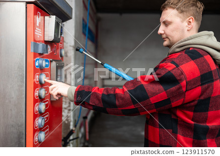Close up of a hand pressing a button on a self-service coin machine at car wash. Close up of a hand pressing a button on a self-service coin machine at car wash. 123911570
