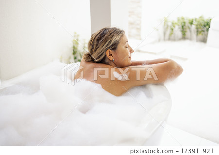 A young woman smiles and takes a bath with fluffy foam. The charming lady has closed her eyes 123911921