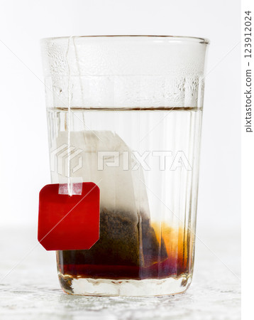 Faceted glass of boiled water and tea bag Faceted glass of boiled water and tea bag 123912024
