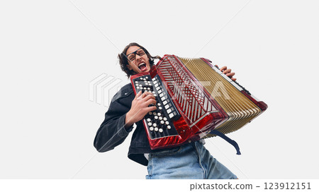 Excited young man, accordion player in black jacket rocking out, playing with energy and passion on white background. 123912151