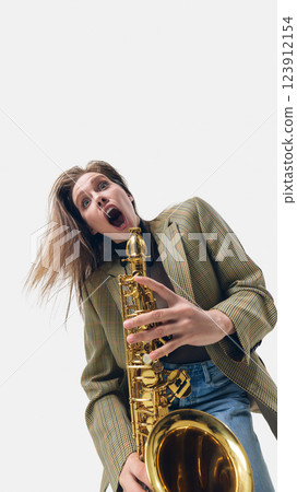 Excited female saxophone player lost in rhythm, dynamic pose amplifying the energy of live jazz, performing on white background 123912154
