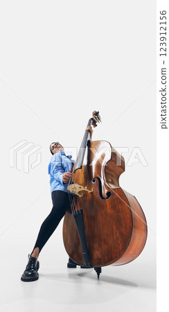 Elegant jazz female bassist with long hair flowing, embracing sound and rhythm in powerful musical expression on white background. 123912156