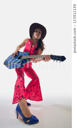Stylish cowgirl in vibrant outfit playing blue guitar with attitude, striking bold pose full of energy against white background. 123912189