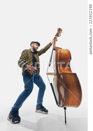 Enthusiastic man, bass player emotionally and passionately playing instrument, expressing raw musical energy against white background. Enthusiastic man, bass player emotionally and passionately playing instrument, expressing raw musical energy against white background. 123912198