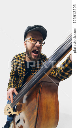 Expressive man, musician unleashing full energy on double bass, wild passion reflected in aggressive playing style. Expressive man, musician unleashing full energy on double bass, wild passion reflected in aggressive playing style. 123912203