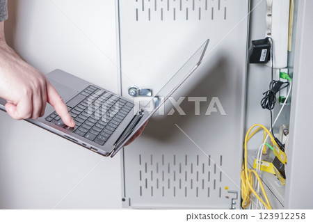 technician using laptop to configure network server in data cabinet for IT maintenance and troubleshooting technician using laptop to configure network server in data cabinet for IT maintenance and troubleshooting 123912258