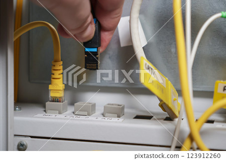technician installing ethernet cable into network panel for internet connection and IT maintenance in server room 123912260