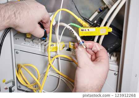 technician connecting network and coaxial cables in server cabinet, internet and tv installation, communication technology concept 123912268