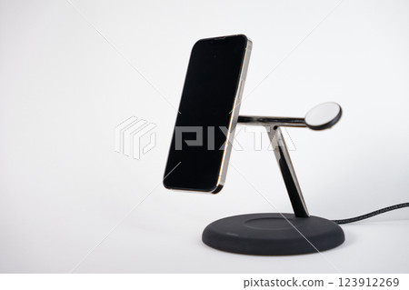 sleek wireless charging stand with smartphone on minimal white background, modern tech accessory for efficient workspace 123912269