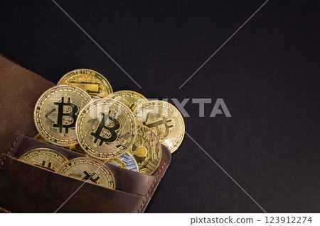 golden bitcoin and cryptocurrency coins in a leather wallet on black background, representing digital currency, blockchain investment, and financial growth 123912274
