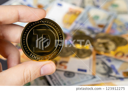 hand holding dogecoin over blurred background of euro and dollar bills, representing cryptocurrency investment and global finance 123912275