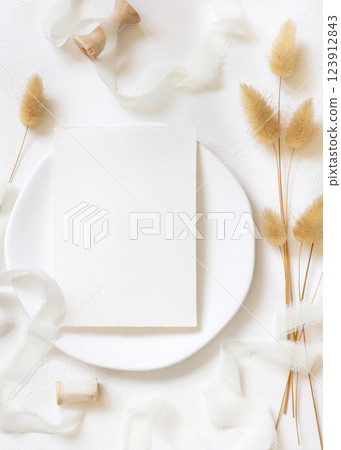 Blank card near silk ribbons and dried hare's tail grass top view on white, boho wedding mockup Blank card near silk ribbons and dried hare's tail grass top view on white, boho wedding mockup 123912843