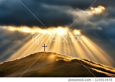 Sunbeams break through thick clouds, casting radiant light onto a small cross on a hill. The image symbolizes divine presence and faith in God 123913478
