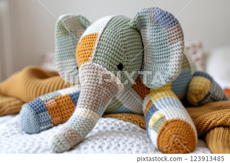 Handmade elephant toy sitting on knitted blanket 123913485
