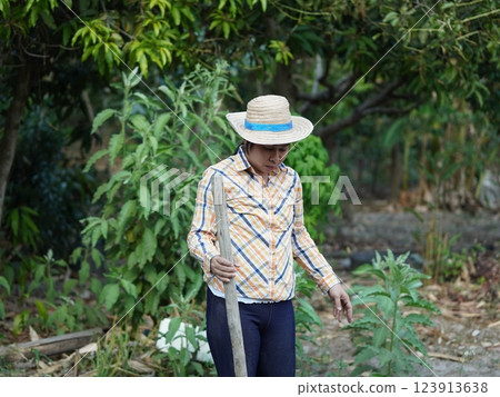 Asian adult woman working outdoors in summer garden. Asian adult woman working outdoors in summer garden. 123913638