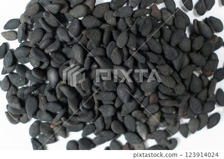 Black sesame seeds scattered on a white background macro top view Black sesame seeds scattered on a white background macro top view 123914024