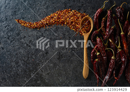 Dried red chili pepper and flakes on a black stone background. 123914429