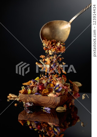 Various dried herbs and spices is poured into a wooden dish. Various dried herbs and spices is poured into a wooden dish. 123914434