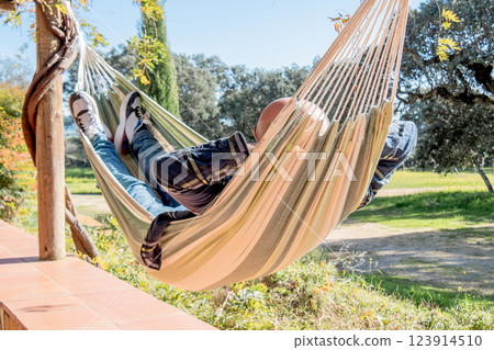 Man relaxing in a hammock outdoors on a sunny day. 123914510