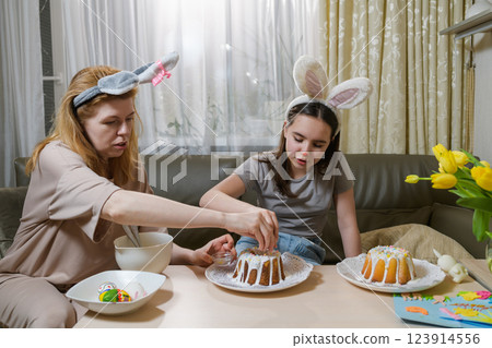 Mother and daughter decorating Easter cakes together. Mother and daughter decorating Easter cakes together. 123914556