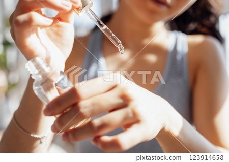 Asian woman applies anti-aging serum with vitamins from pipette Asian woman applies anti-aging serum with vitamins from pipette 123914658
