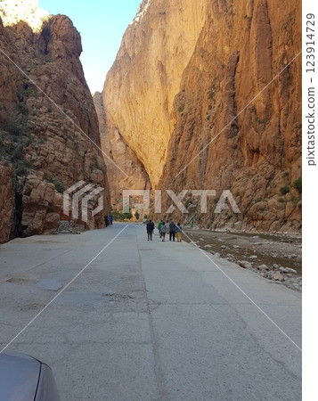 A car is currently driving down a scenic road that runs next to a mountain A car is currently driving down a scenic road that runs next to a mountain 123914729