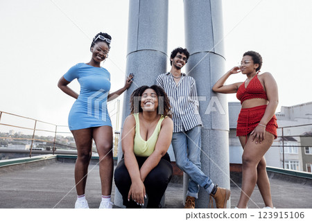 Company of four multi-ethnic people pose on roof of multi-storey house 123915106