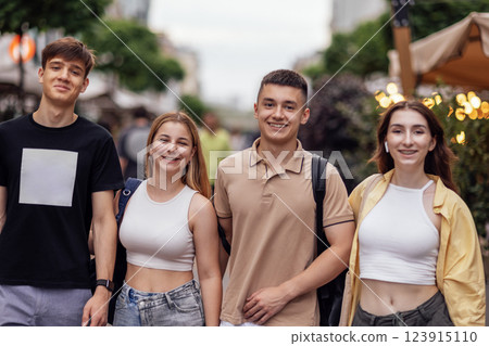 Four friends in casual clothes are walking around the city. Teenagers laugh and have fun together. Two guys and two girls outdoors on the street. Four friends in casual clothes are walking around the city. Teenagers laugh and have fun together. Two guys and two girls outdoors on the street. 123915110