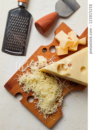 Grated cheese, Maasdam, on a cutting board, grater and cheese knife, close-up, no people, Grated cheese, Maasdam, on a cutting board, grater and cheese knife, close-up, no people, 123915258