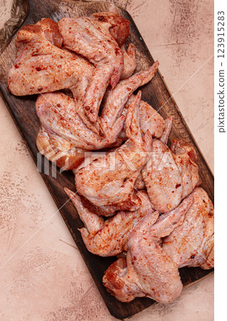 Chicken wings, marinated and laid out on a wooden platter, ready for cooking, grilling or baking, in a home kitchen, there are no people 123915283