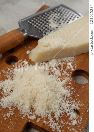 Freshly sliced and grated cheese, parmesan cheese, on a wooden chopping board, rustic style, no people Freshly sliced and grated cheese, parmesan cheese, on a wooden chopping board, rustic style, no people 123915284